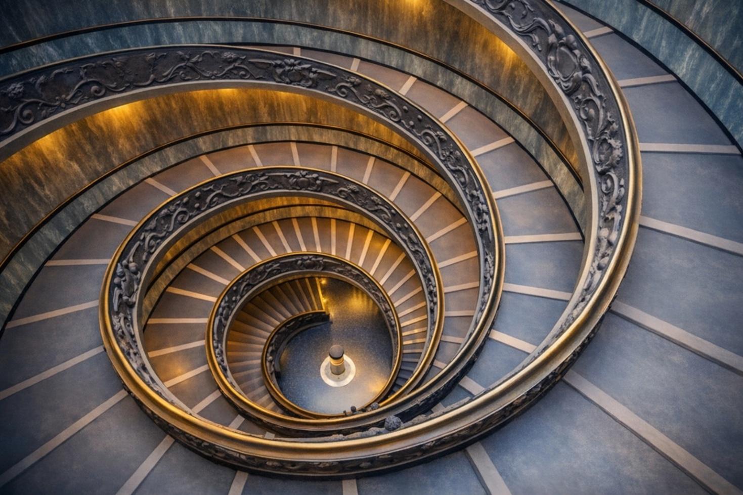 A descending bronze and stone spiral staircase.